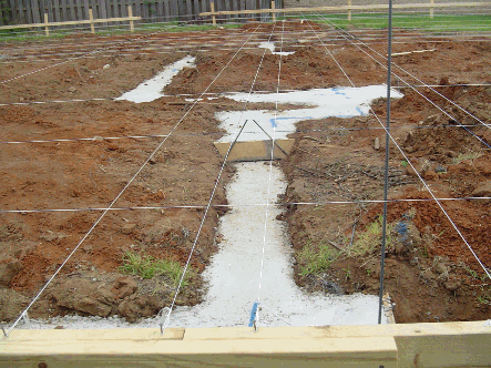 Layout strings pulled to batter boards, across concrete footings.